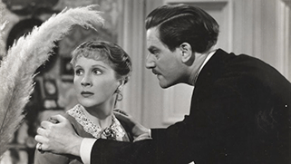 Zwart-wit beeld van een oude film waarbij een man een vrouw vasthoudt