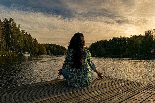 Woman sitting cross-legged by the water