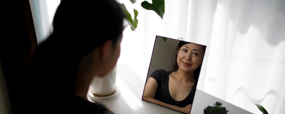 Vrouw die in de spiegel kijkt en zichzelf accepteert