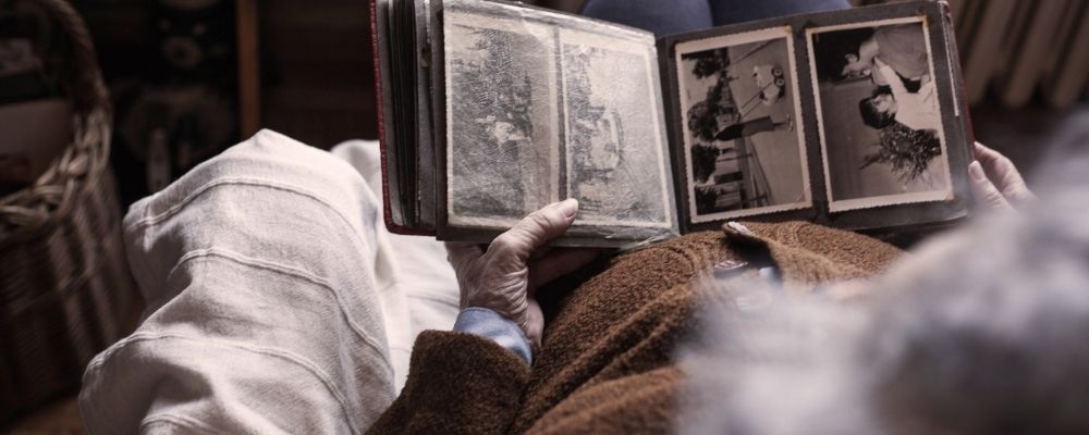Oude vrouw die een fotoboek van vroeger vastheeft