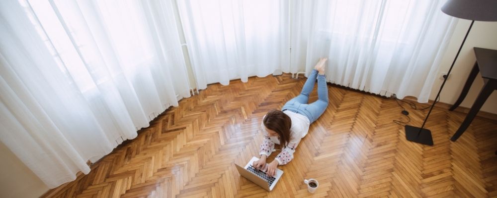 Vrouw ligt alleen op de grond met haar laptop