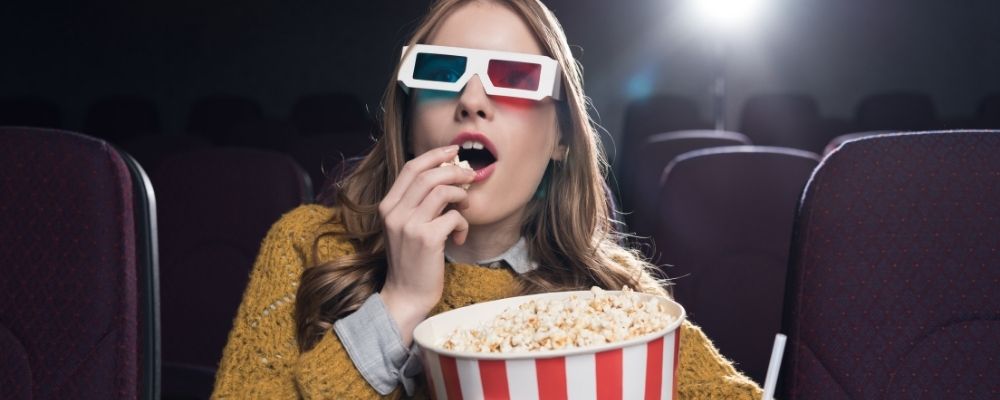 Vrouw zit in de bioscoop naar een 3d film te kijken en popcorn te eten