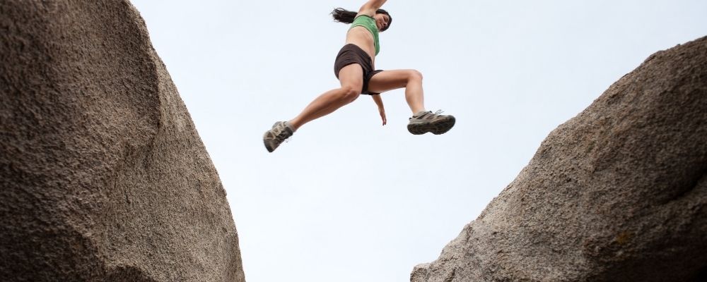 Vrouw die van de ene rots naar de andere rots springt