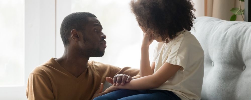 Empathische vader  knielt voor zijn huilende dochter