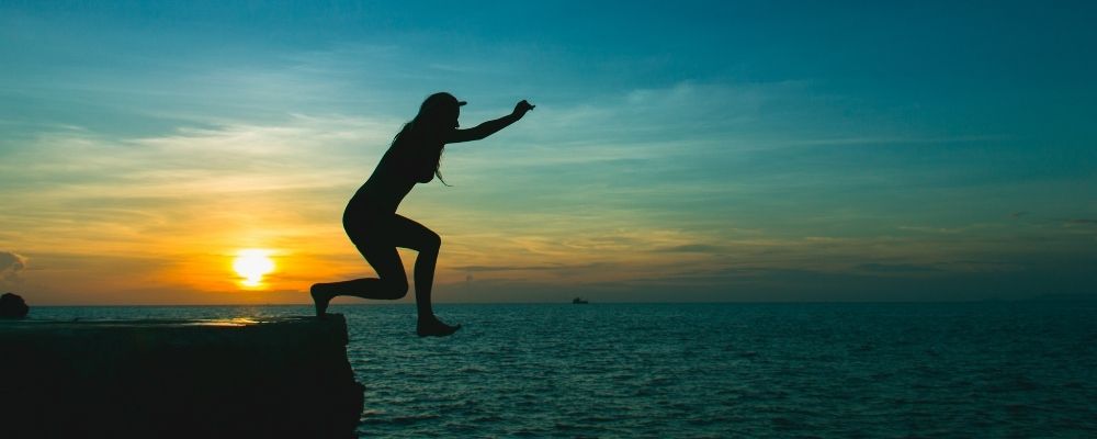 Vrouw springt zonder angst van een rots het water in