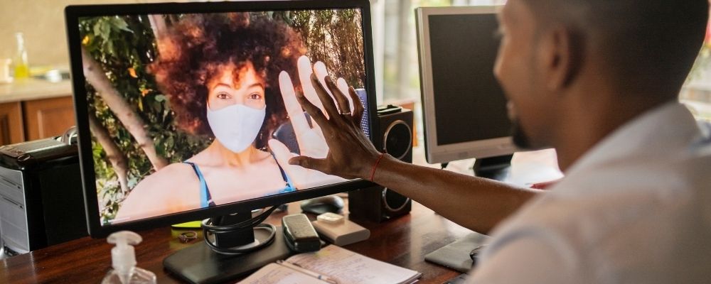 Man videobelt met een vrouw en houdt zijn hand tegen het computerscherm