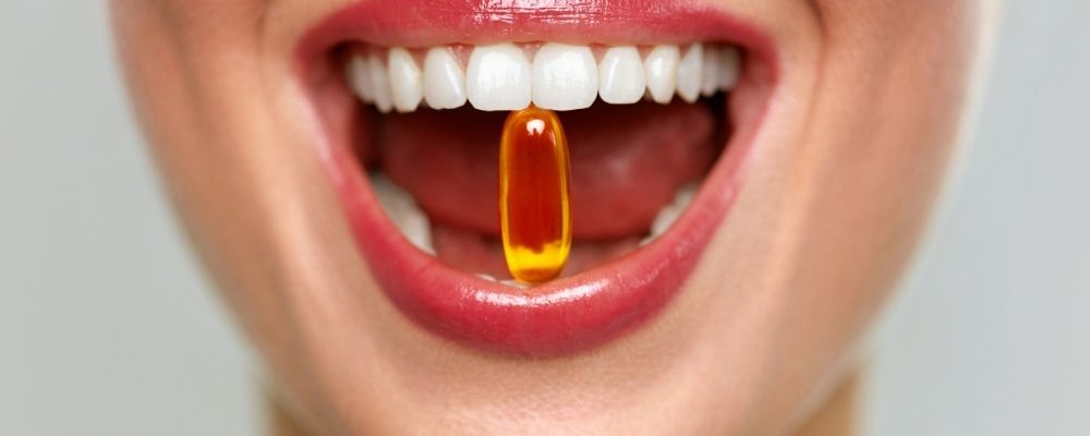 Vrouw met een vitaminesupplement in haar mond