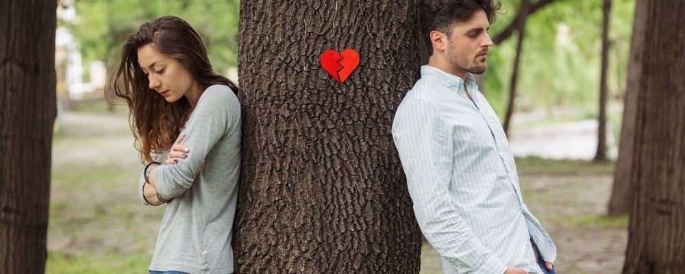 Man en vrouw die tegen een boom aanleunen met een gebroken hart ertussen