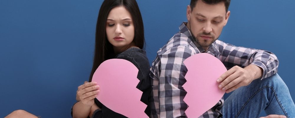 Man en vrouw die beide een helft van een papieren hart vasthebben