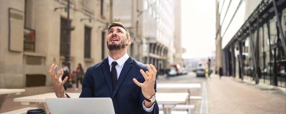 Man looking up with his hands up frustrated