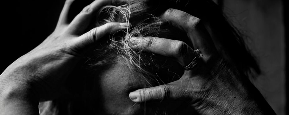 Zwart wit foto van iemand die met zijn handen in zijn haren zit