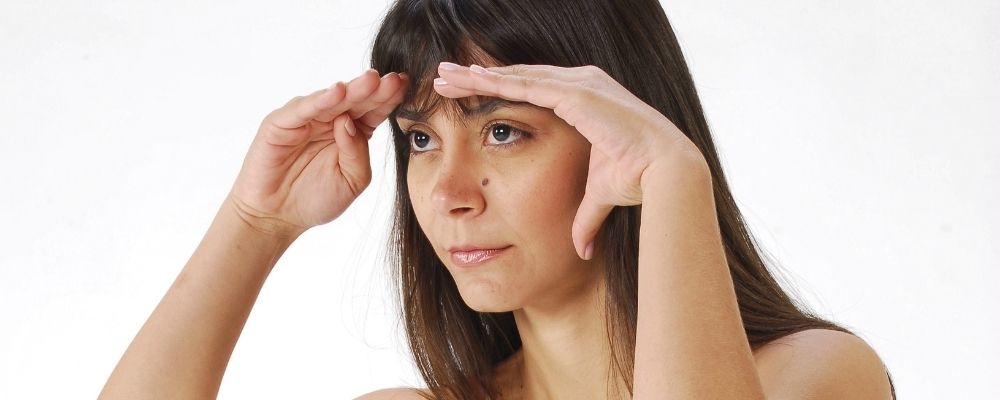 Woman holding her hands above her eyes and looking far away