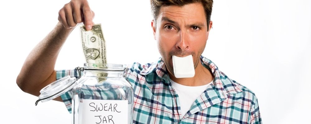 Man die een papiertje in zijn mond heeft en briefgeld stopt in een 'niet-schelden pot'
