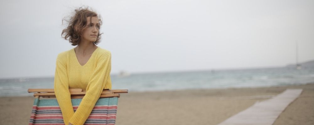 Vrouw die onzeker uitkijkt over het strand