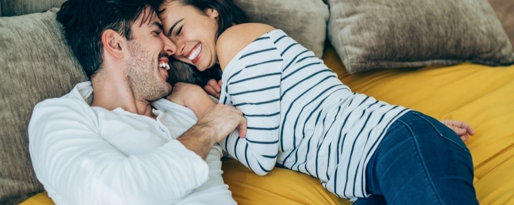 Man en vrouw die samen op bed liggen en lachen