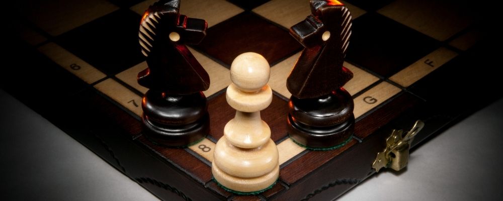 Twee paarden op een schaakbord die een pion omsingelen
