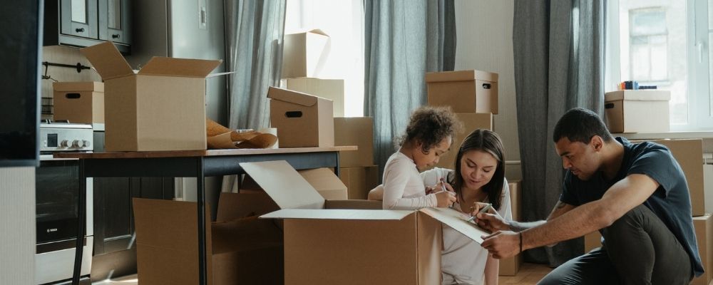 Man, vrouw en dochter schrijven informatie op verhuisdozen