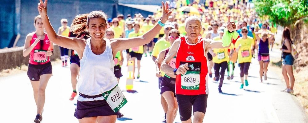 Vrouw die een marathon loopt en met haar armen in de lucht erg blij lacht