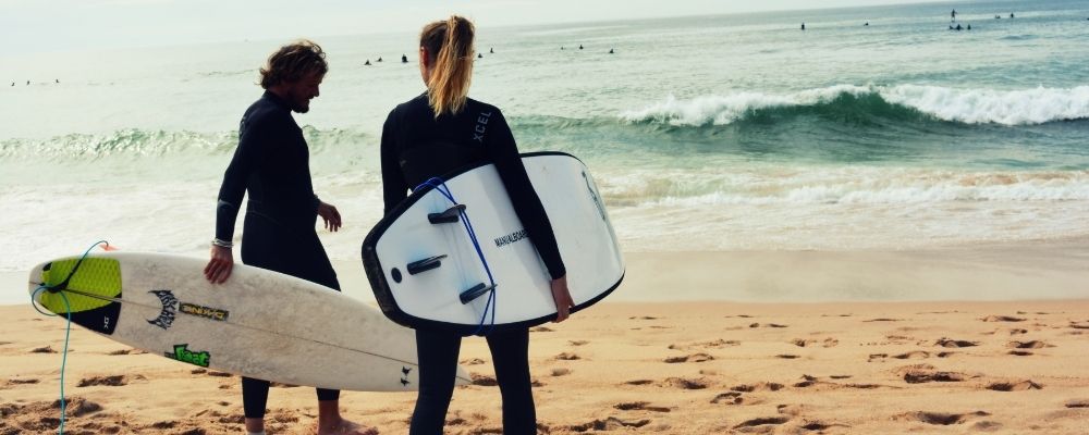 Twee mensen die naar de zee kijken met surfborden in hun hand