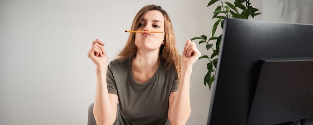 Vrouw die haar werk uitstelt en een potlood tussen haar neus en lippen houdt