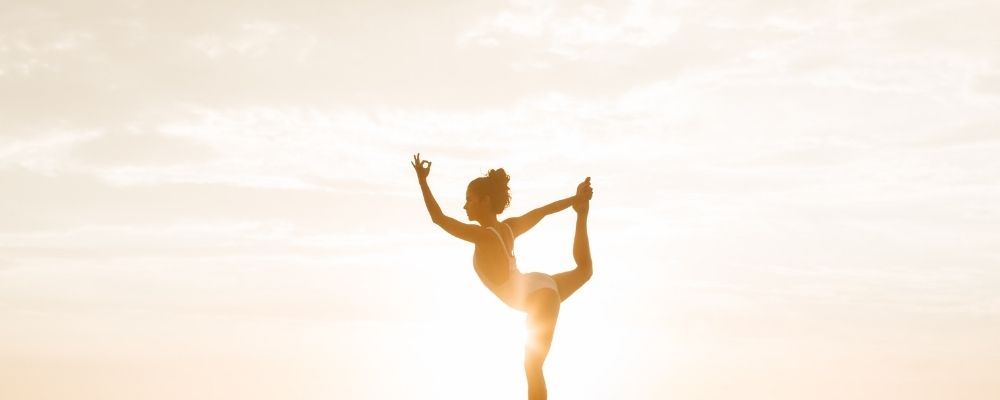 Vrouw die buiten bij zonsondergang een yoga pose doet